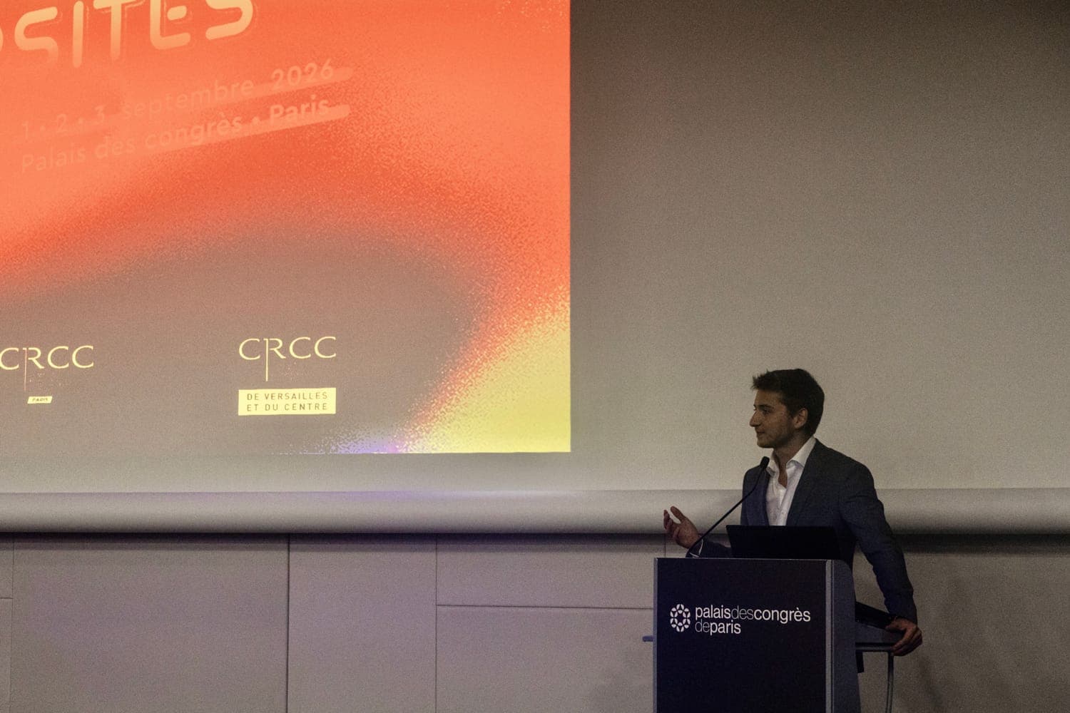 Au pupitre, devant l'écran de la conférence, au Palais des congrès de Paris.